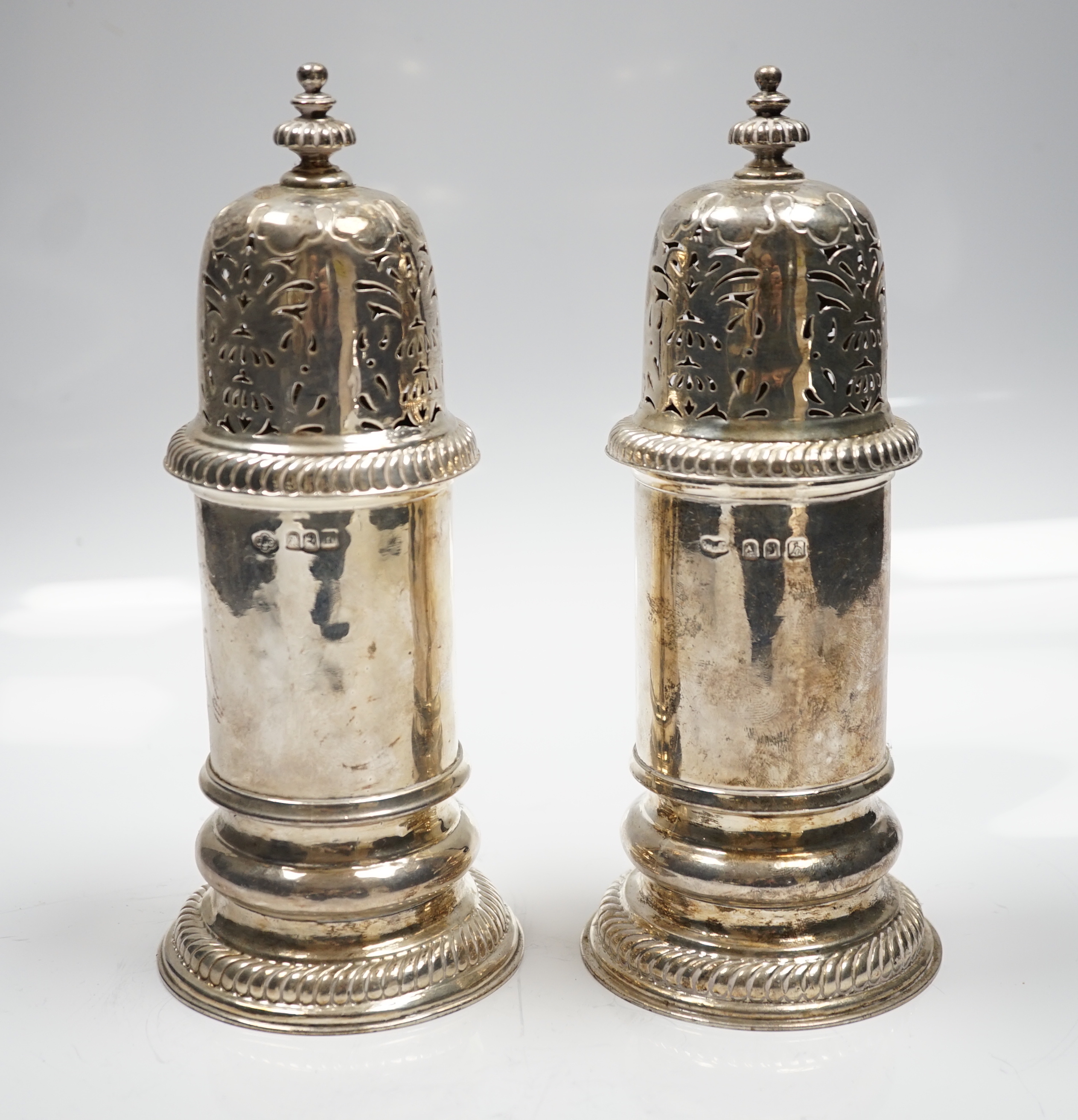 A matched pair of Britannia standard silver lighthouse sugar casters, Carrington & Co, London, 1903 and Wilson & Gill, London, 1963, 20.8cm, 22.6oz.